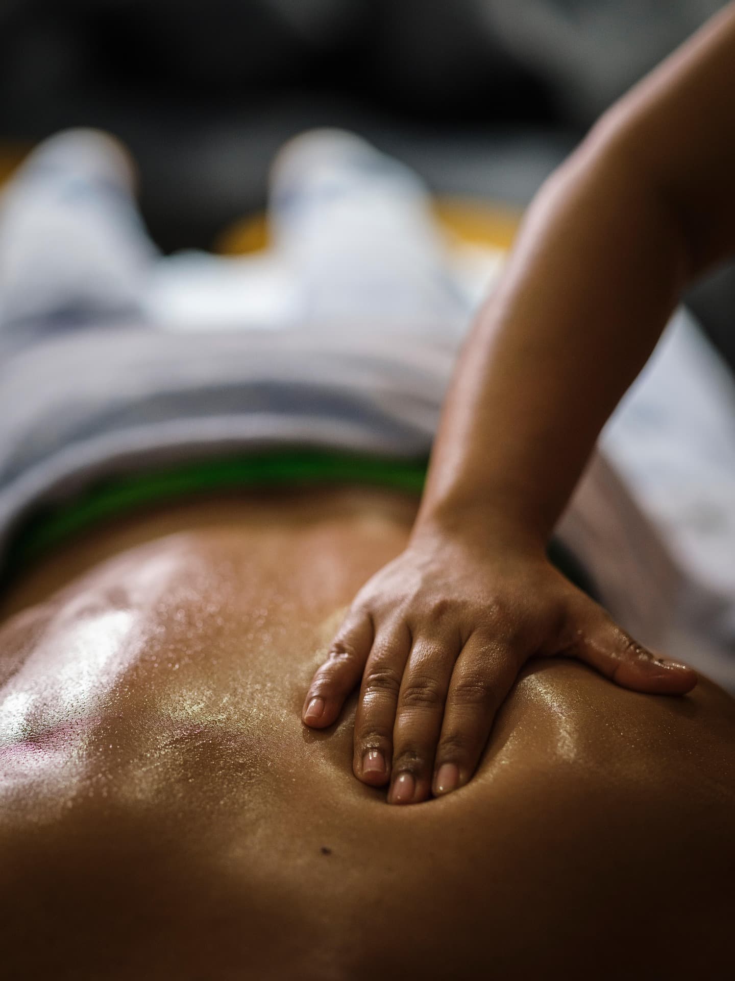 Hände geben eine entspannende Rückenmassage bei gedämpftem Licht